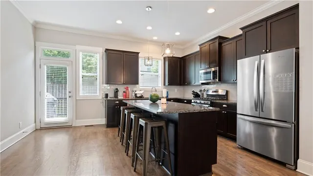 a kitchen with stainless steel appliances granite countertop a refrigerator a sink dishwasher a stove and a refrigerator