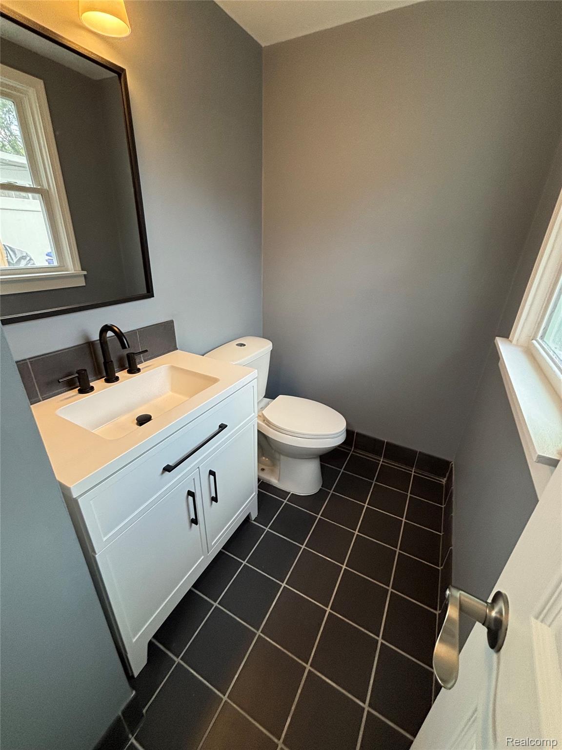 18259 Spring Court South Fraser, MI 48026 - Photo 56 of 60 White vanity with a single basin sink, matte black faucet, and dark tiled backsplash