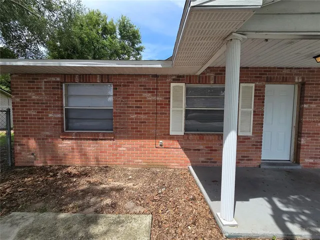 an empty room with kitchen and chandelier fan