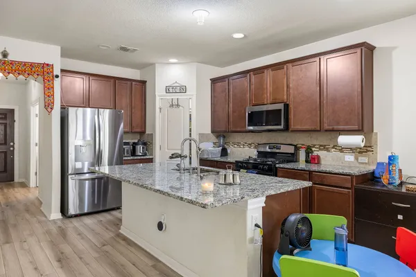 a kitchen with stainless steel appliances granite countertop a refrigerator a stove top oven a sink and dishwasher