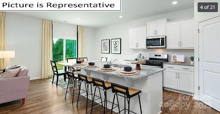 1365 Secrest Cmns Drive Monroe, NC 28112 - Photo 3 of 8 a kitchen with stainless steel appliances kitchen island granite countertop a stove a sink a dining table and chairs