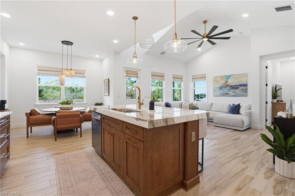 6975 Saona Court Naples, FL 34113 - Photo 8 of 30 a kitchen with kitchen island granite countertop a sink and a living room view