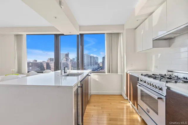 a kitchen with stainless steel appliances kitchen island granite countertop a refrigerator a stove a sink dishwasher and white cabinets with wooden floor