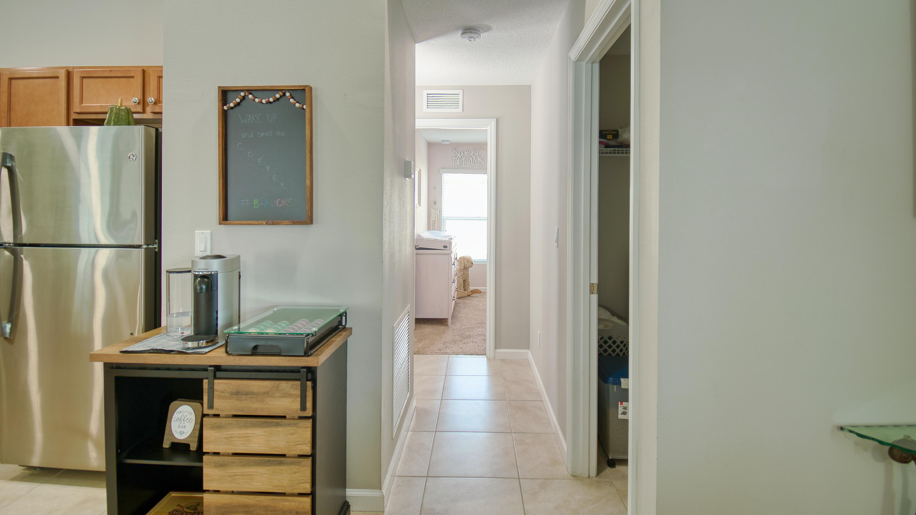 1780 Southwest Leafy Road Port St. Lucie, FL 34953 - Photo 18 of 30 a hallway with cabinets and a refrigerator
