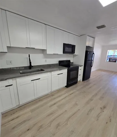 a kitchen with granite countertop a sink stove and cabinets