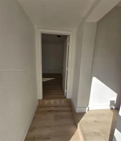 a view of a hallway with wooden floor and entryway