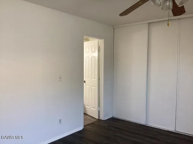 a view of an empty room with wooden floor and closet