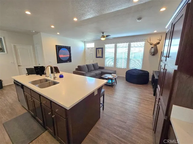 a large kitchen with stainless steel appliances a stove a sink a refrigerator and a dining table with wooden floor