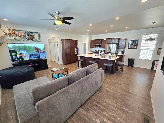 a living room with furniture and kitchen view with wooden floor