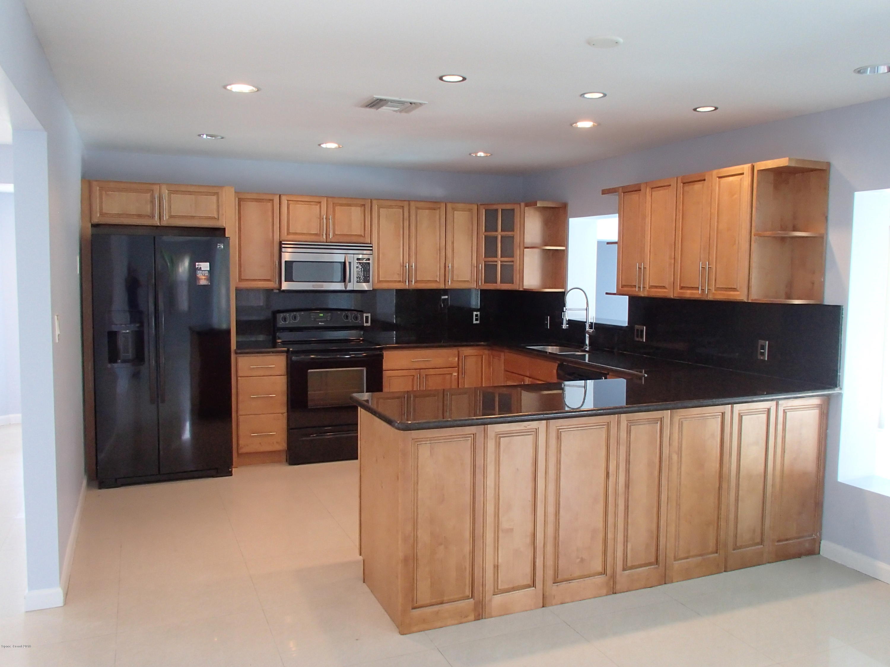 703 Bermuda Road Cocoa Beach, FL 32931 - Photo 2 of 19 a kitchen with stainless steel appliances granite countertop a refrigerator and a stove