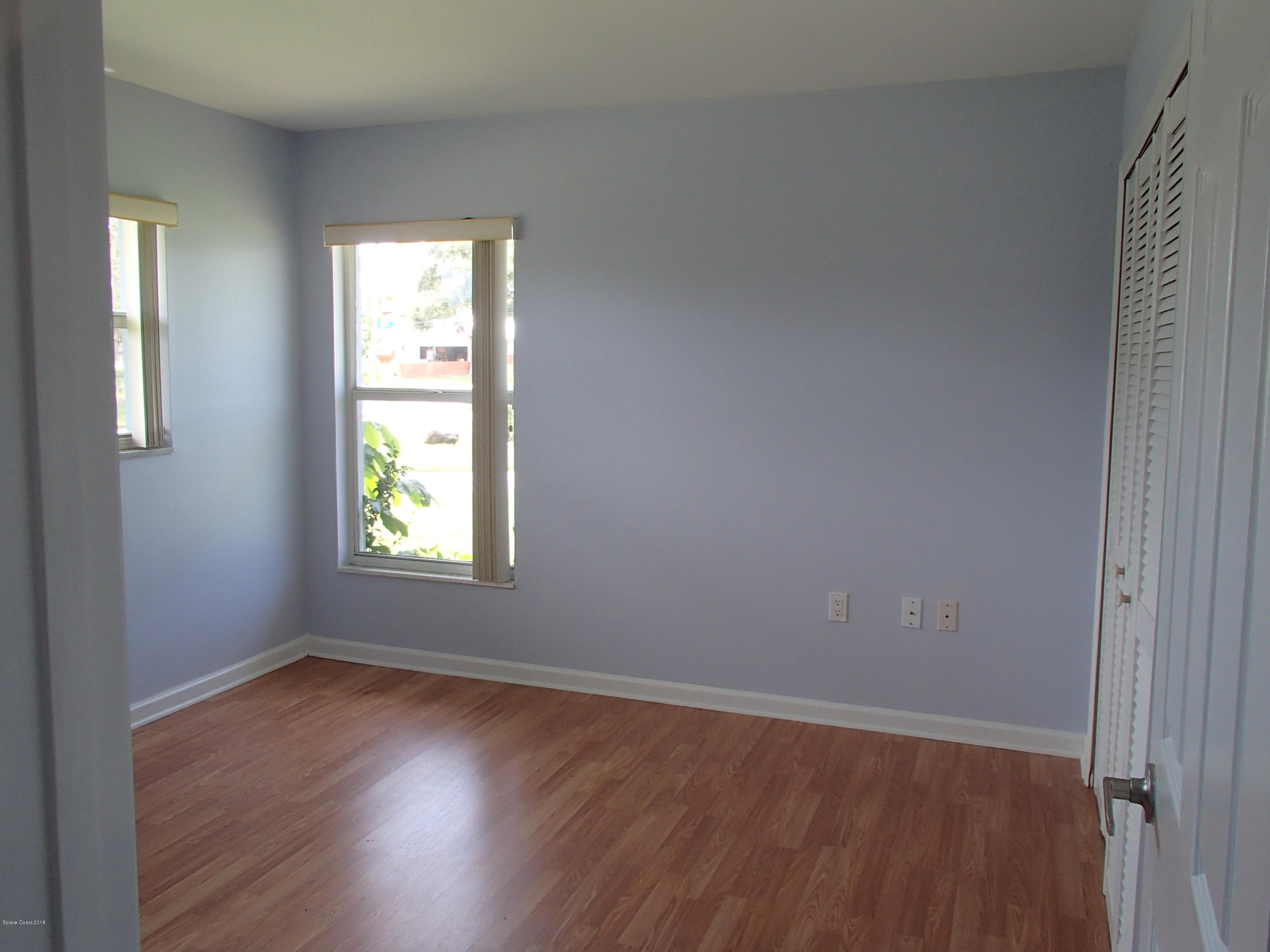 703 Bermuda Road Cocoa Beach, FL 32931 - Photo 11 of 19 an empty room with wooden floor and windows