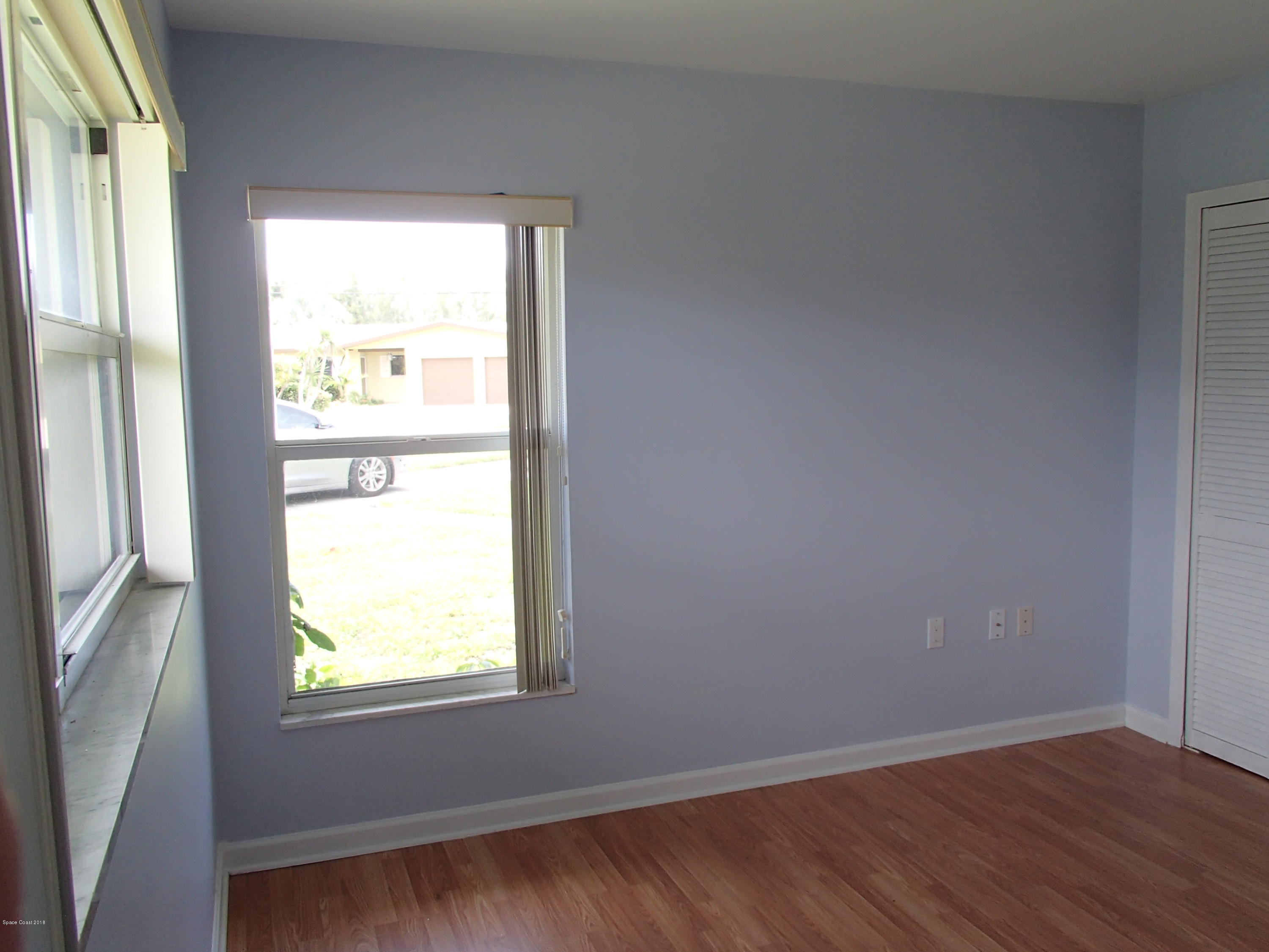 703 Bermuda Road Cocoa Beach, FL 32931 - Photo 13 of 19 a view of an empty room with wooden floor and a window