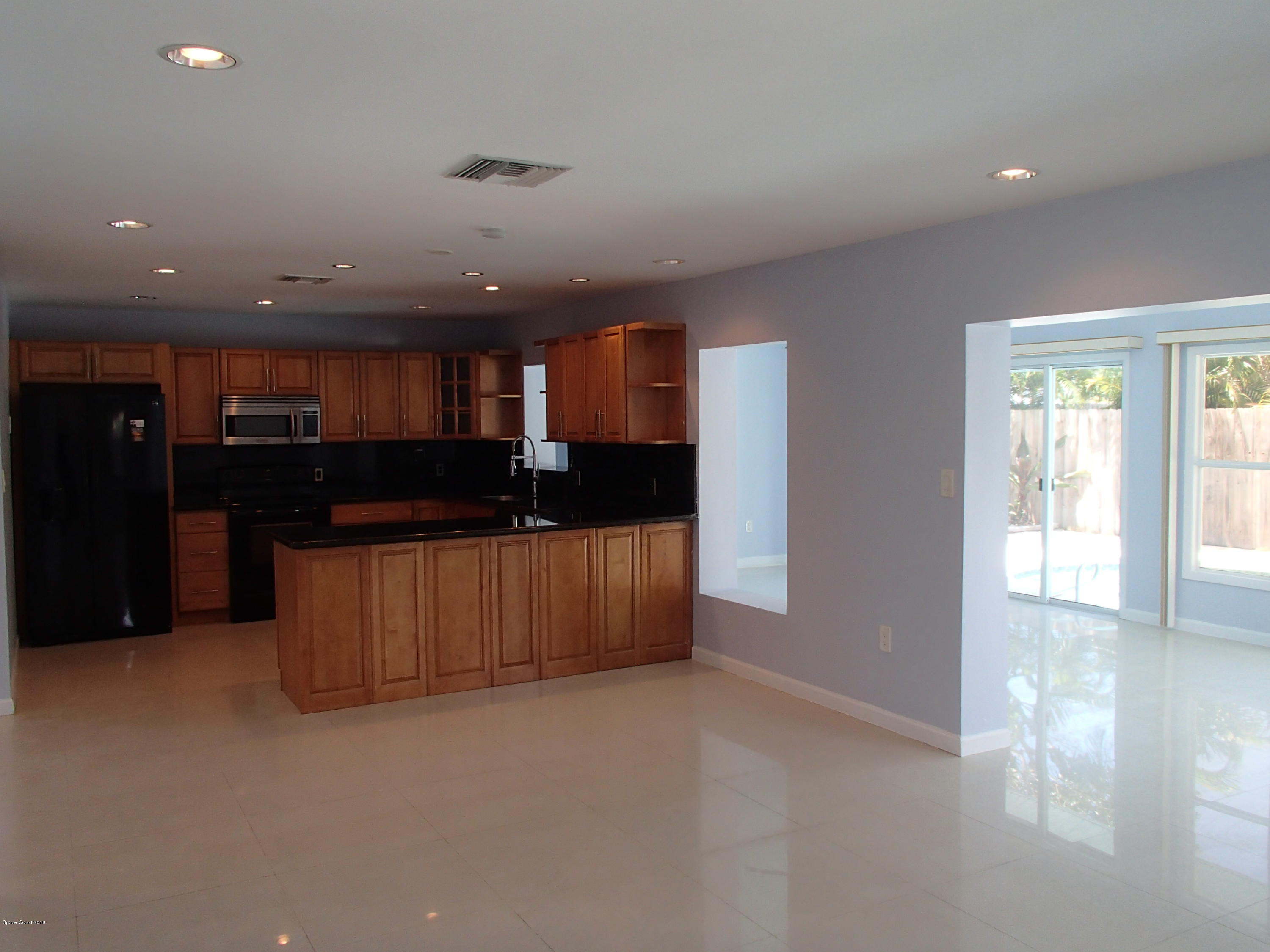 703 Bermuda Road Cocoa Beach, FL 32931 - Photo 3 of 19 a kitchen with a refrigerator and a counter top space