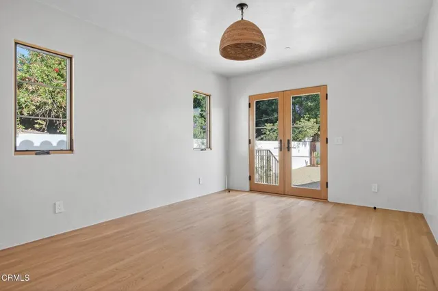 a view of an empty room with a window and wooden floor