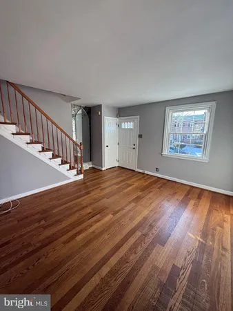 a view of an empty room with wooden floor and stairs