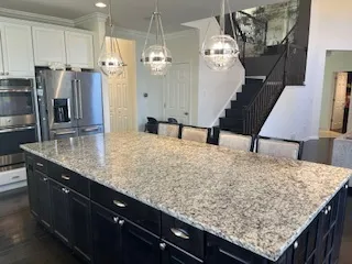 a kitchen with kitchen island granite countertop a sink a refrigerator and wooden floor