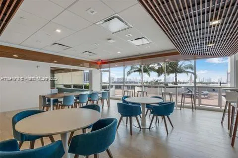 a dining hall with stainless steel appliances a dining table and chairs with wooden floor