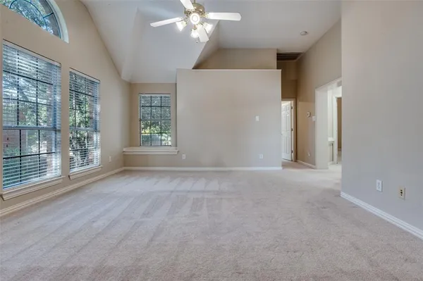 en empty room with windows and chandelier fan