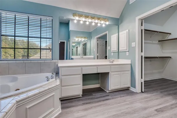 a bathroom with a double vanity sink mirror and bathtub