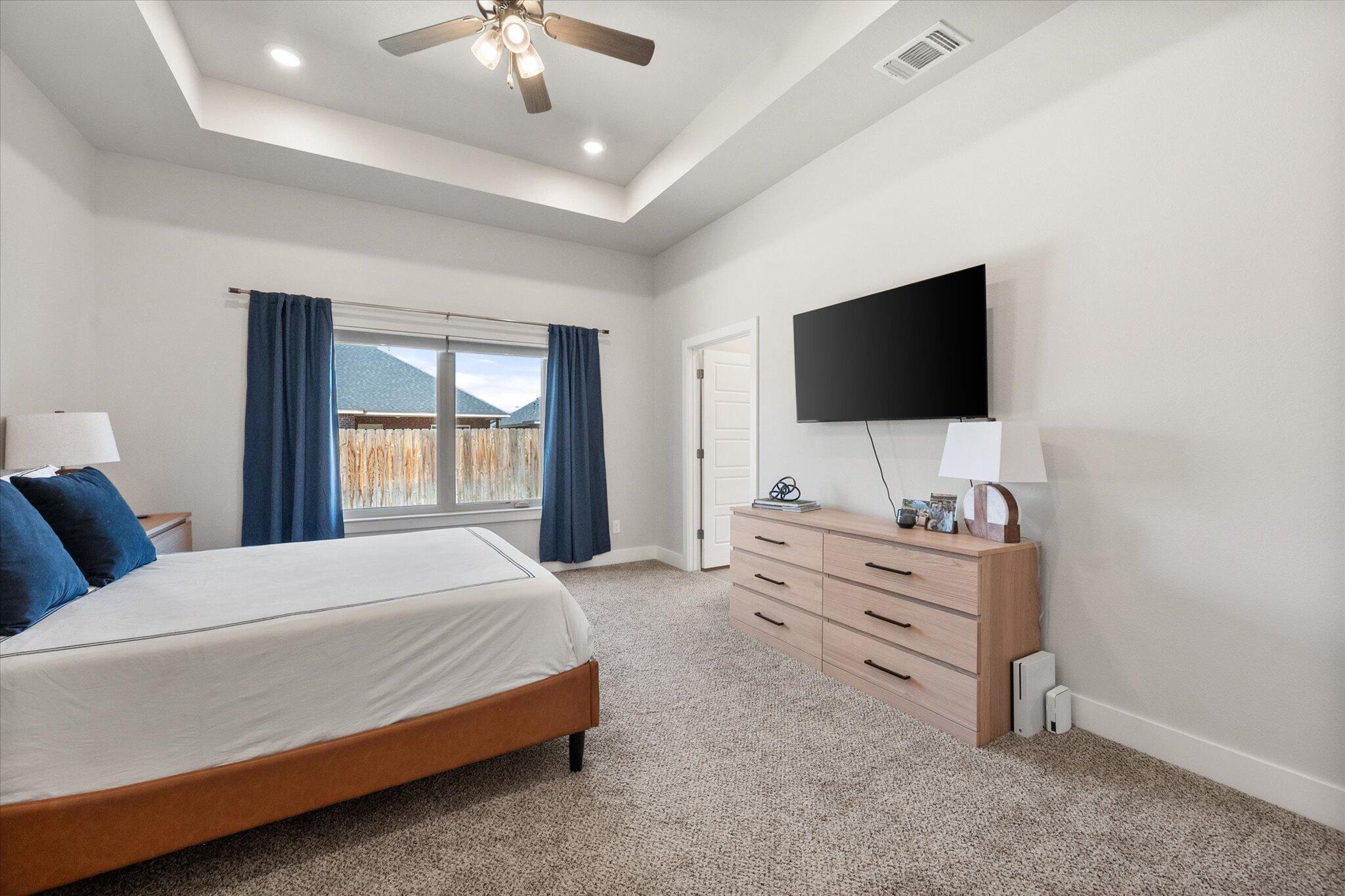5908 Grinnell Street Lubbock, TX 79416 - Photo 13 of 27 a spacious bedroom with a bed and a flat screen tv