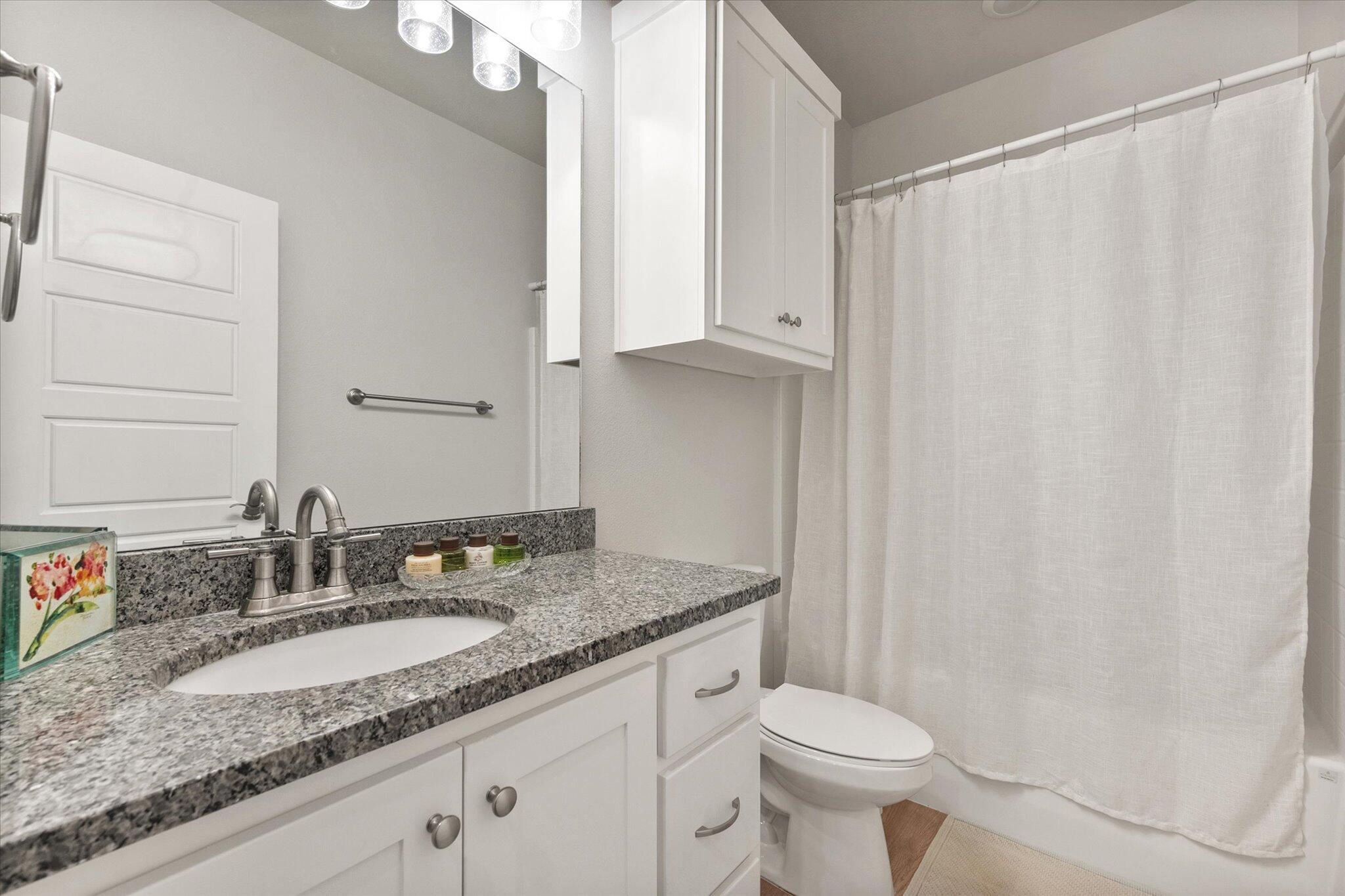 5908 Grinnell Street Lubbock, TX 79416 - Photo 21 of 27 a bathroom with a granite countertop sink and a mirror