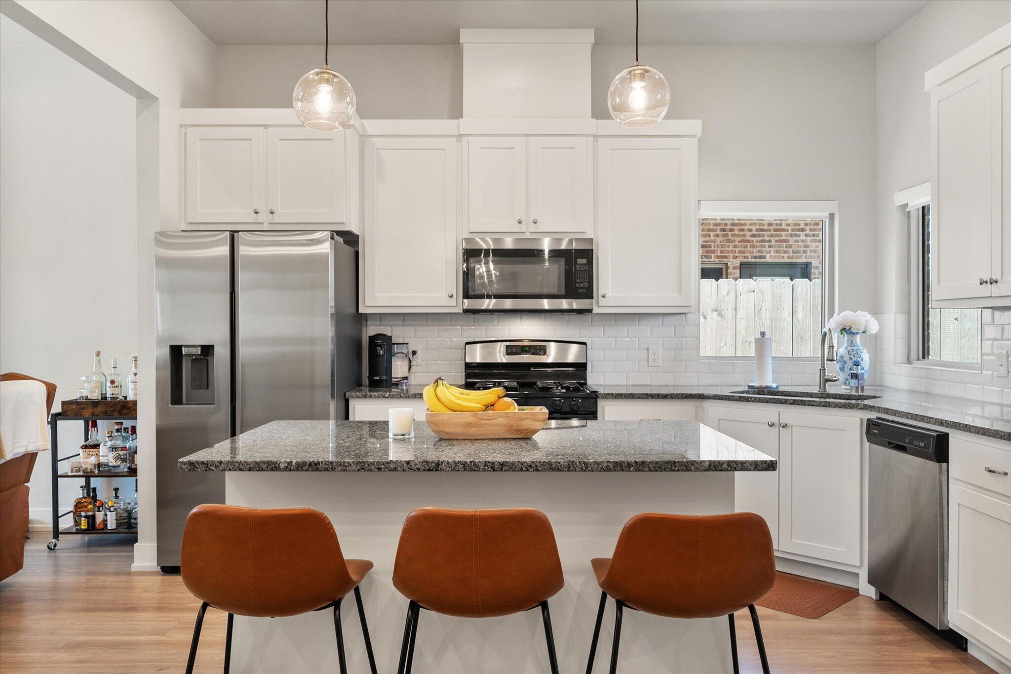 5908 Grinnell Street Lubbock, TX 79416 - Photo 8 of 27 a kitchen with stainless steel appliances granite countertop a stove top oven a refrigerator a sink and chairs