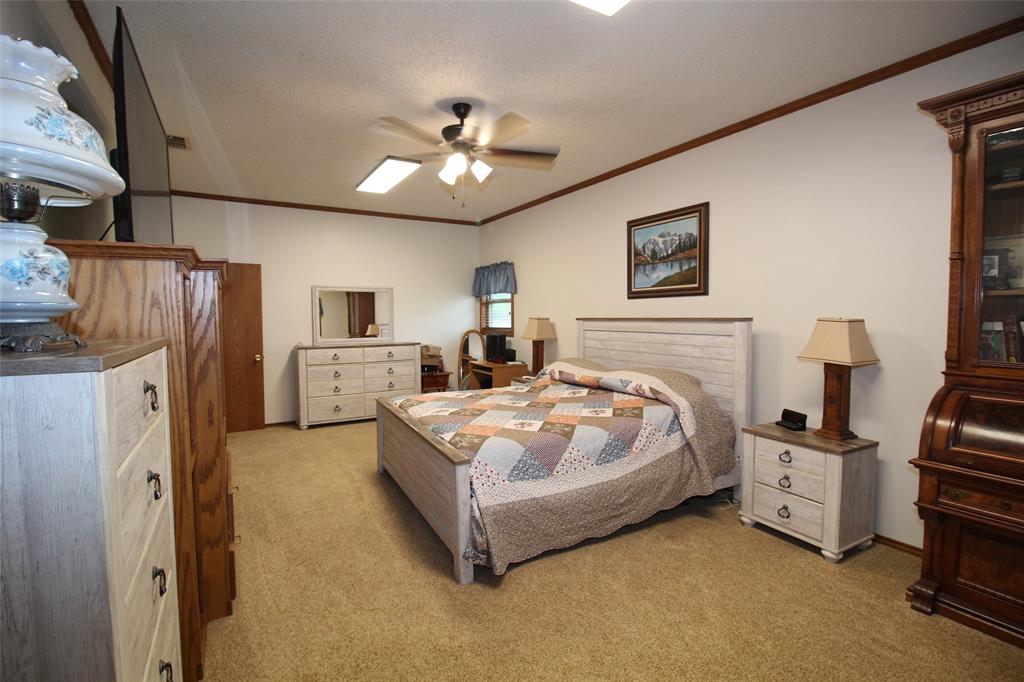 220 North 14th Avenue Munday, TX 76371 - Photo 13 of 34 a spacious bedroom with a bed and a chandelier