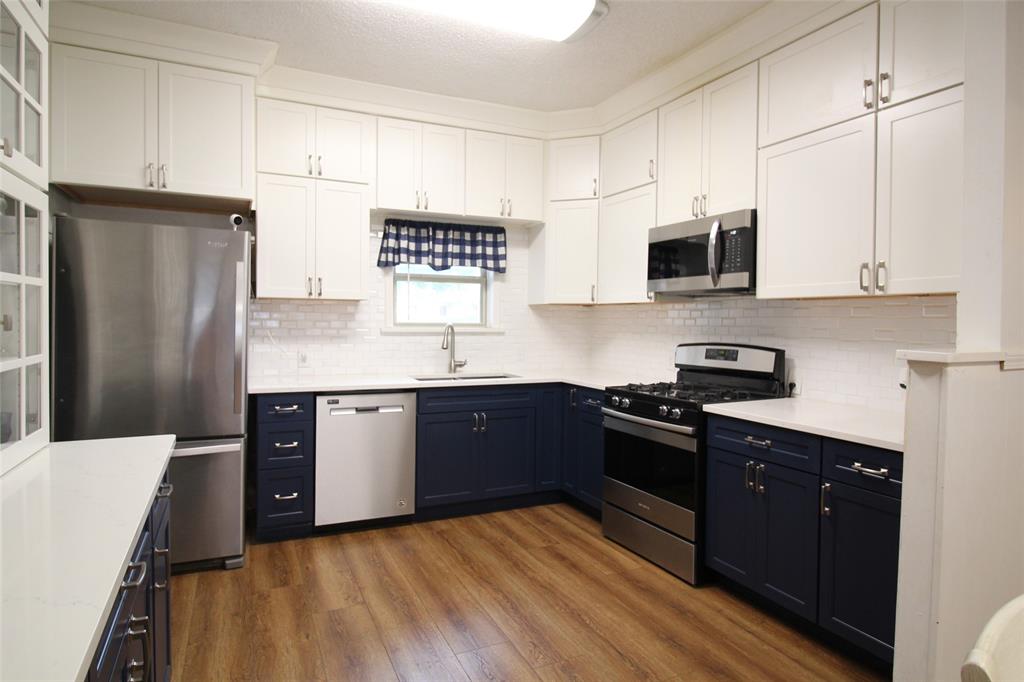 220 North 14th Avenue Munday, TX 76371 - Photo 9 of 34 a kitchen with stainless steel appliances granite countertop a refrigerator a stove top oven a sink and dishwasher
