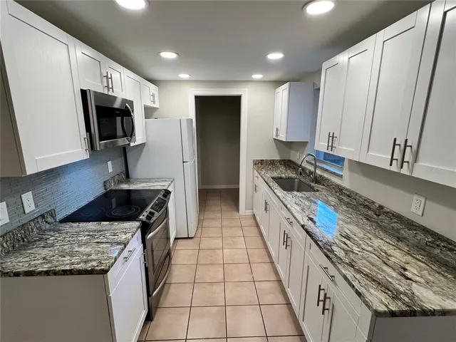 a kitchen with stainless steel appliances granite countertop a stove a sink and a microwave