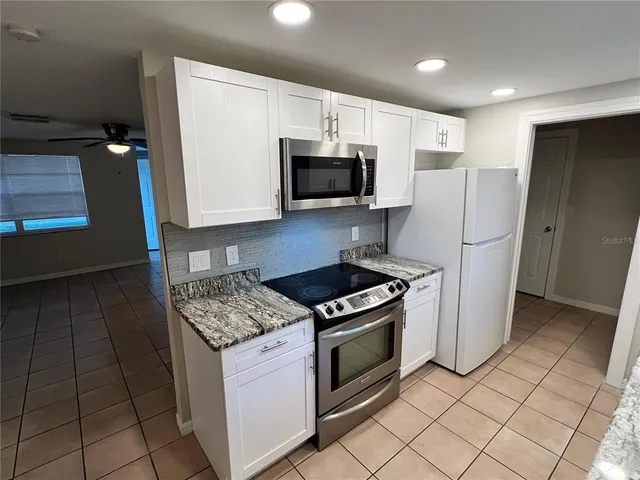 a kitchen with granite countertop a refrigerator and a stove top oven
