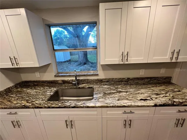 a kitchen with granite countertop a sink a stove and cabinets