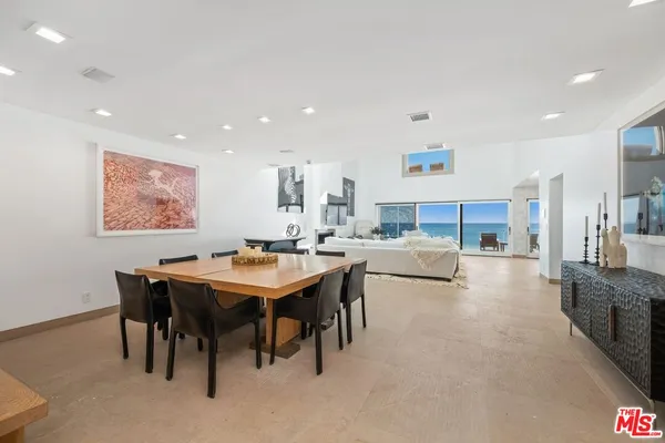 a living room with stainless steel appliances a table and chairs