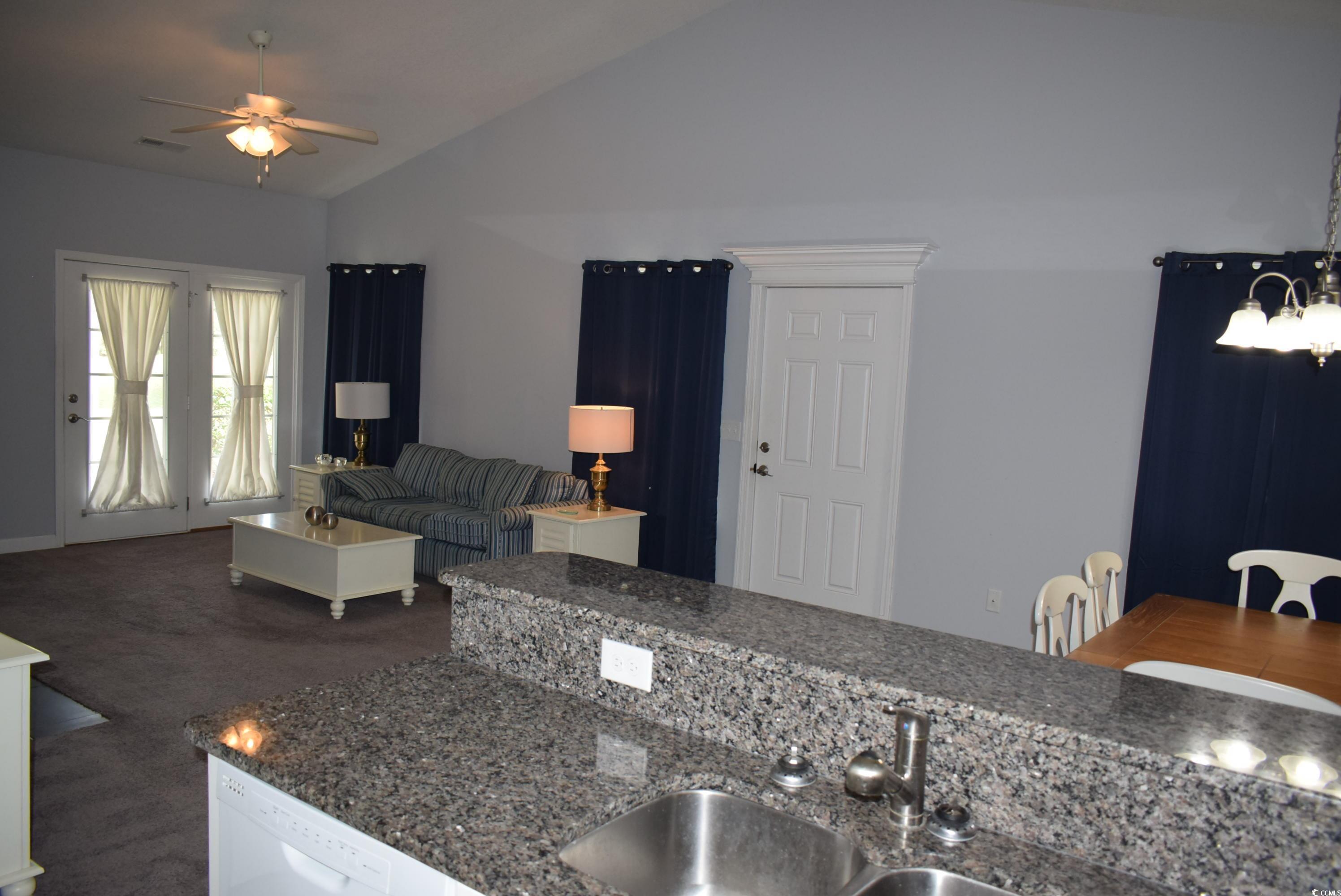 216 Rose Water Loop Myrtle Beach, SC 29588 - Photo 12 of 40 Kitchen featuring dark colored carpet, vaulted ceiling, white dishwasher, a ceiling fan, and dark stone counters