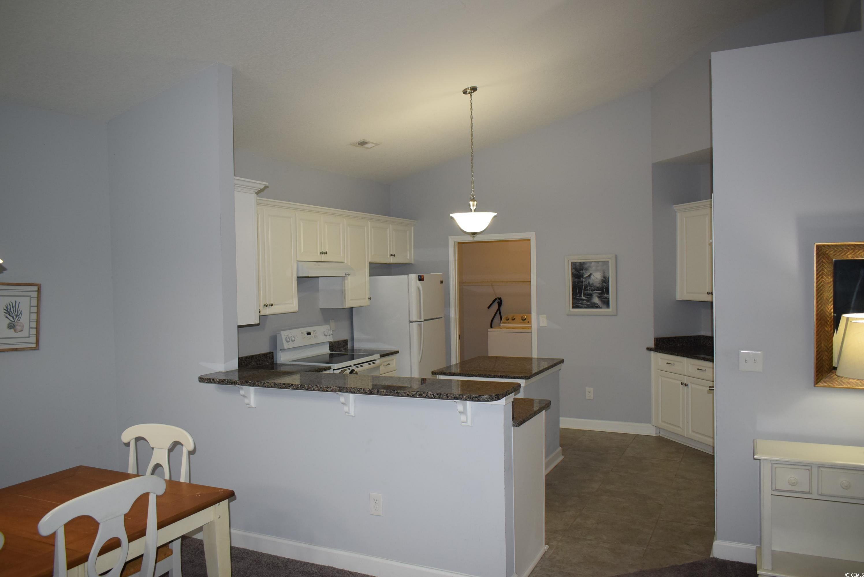 216 Rose Water Loop Myrtle Beach, SC 29588 - Photo 6 of 40 Kitchen featuring lofted ceiling, white appliances, pendant lighting, a peninsula, and a breakfast bar