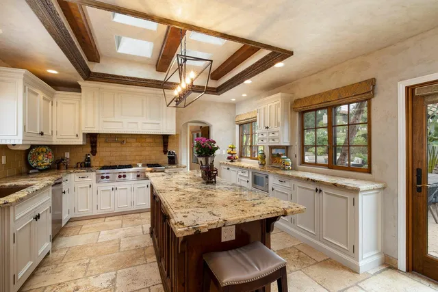 a kitchen with granite countertop a stove dining table and chairs