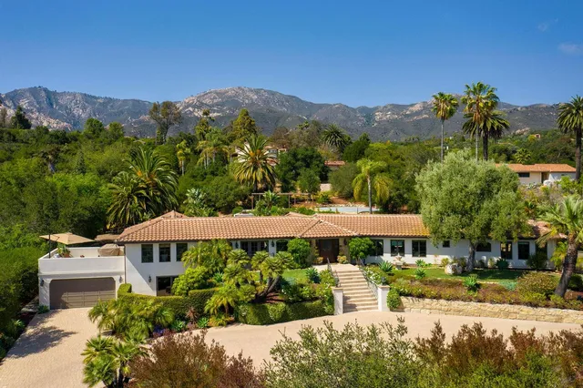 a front view of a house with a yard and mountain