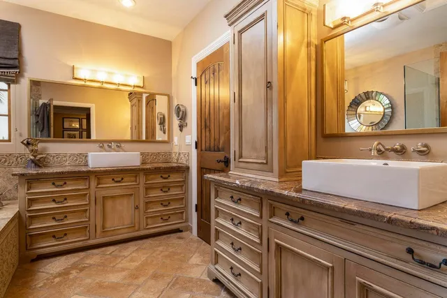a spacious bathroom with a granite countertop double vanity sink a mirror and a bathtub