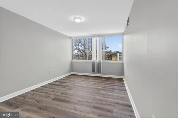 a view of an empty room with wooden floor and a window