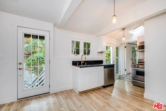 a kitchen with stainless steel appliances a stove top oven a refrigerator a sink and dishwasher with wooden floor