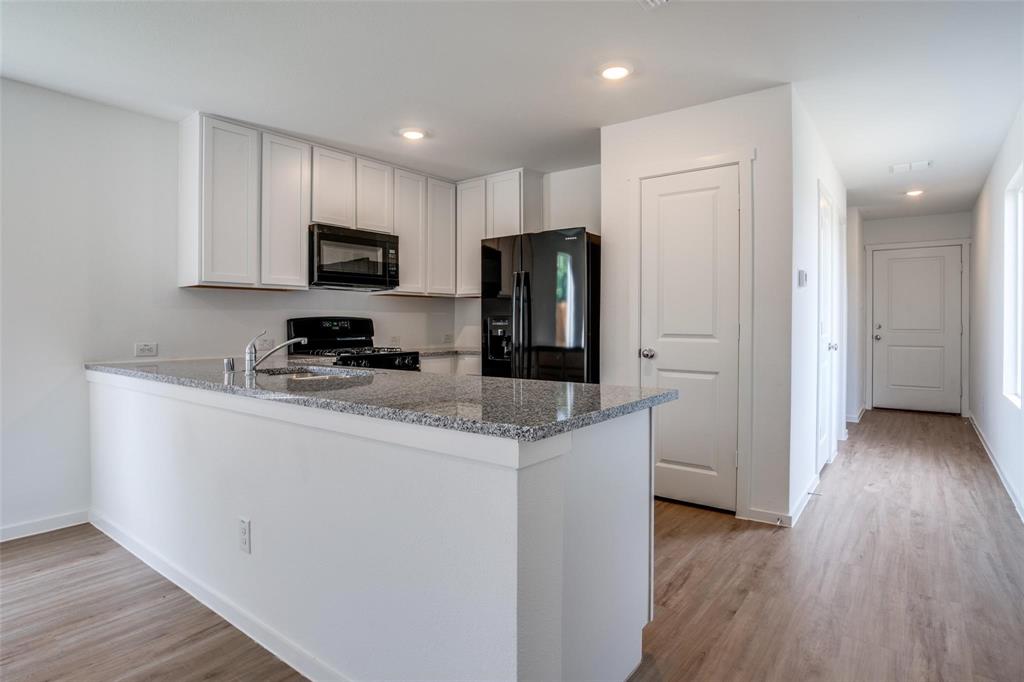 4237 Haflinger Road Providence Village, TX 76227 - Photo 2 of 14 a kitchen with stainless steel appliances granite countertop a stove top oven a refrigerator a sink and dishwasher with wooden floor