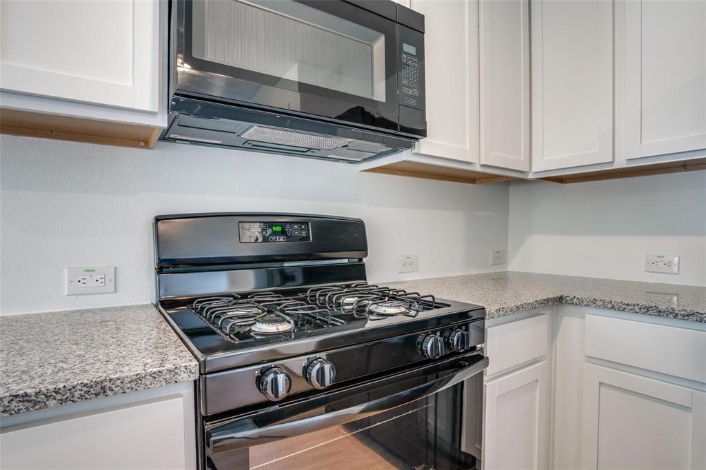 4237 Haflinger Road Providence Village, TX 76227 - Photo 3 of 14 a kitchen with stainless steel appliances granite countertop white cabinets and a stove top oven
