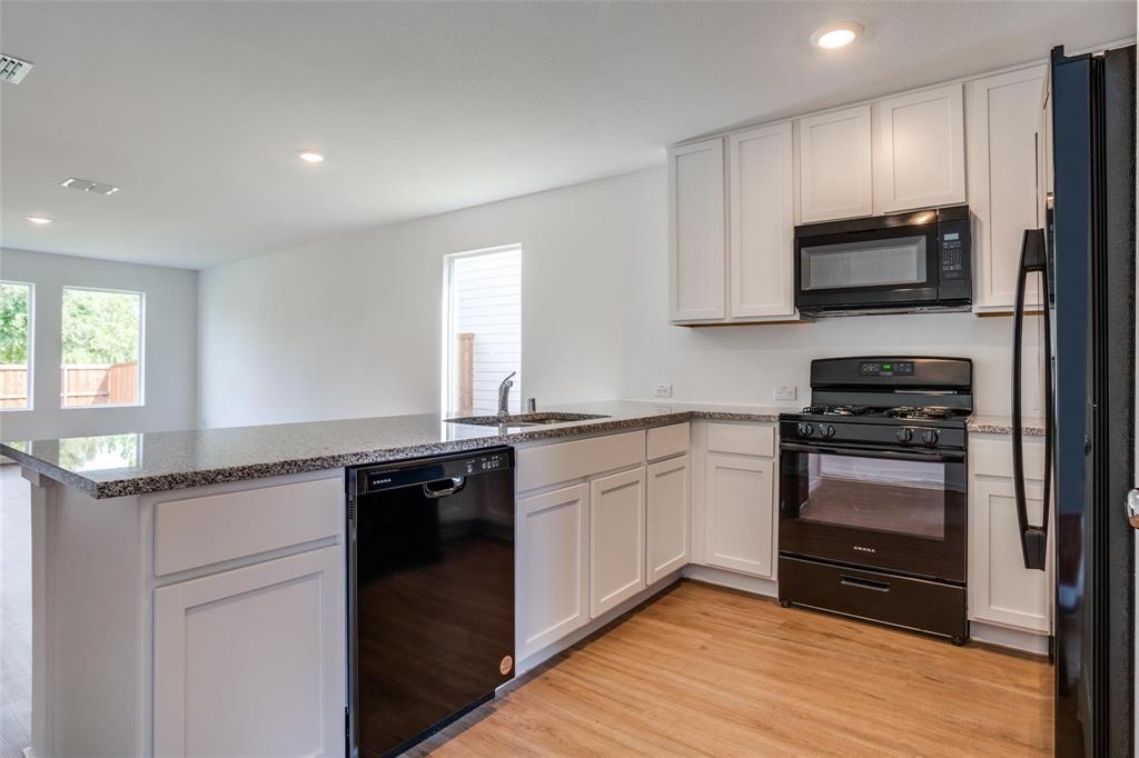 4237 Haflinger Road Providence Village, TX 76227 - Photo 4 of 14 a kitchen with granite countertop stainless steel appliances and wooden cabinets