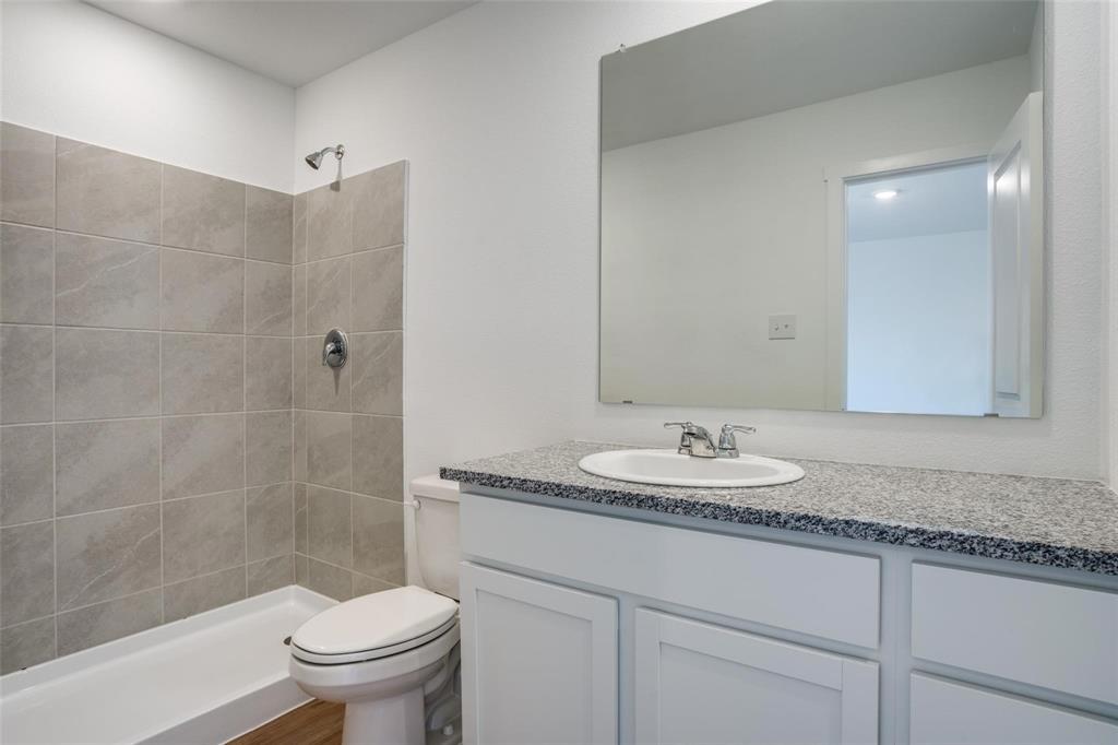 4237 Haflinger Road Providence Village, TX 76227 - Photo 6 of 14 a bathroom with a granite countertop sink a toilet and a mirror