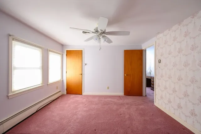 an empty room with windows and fan