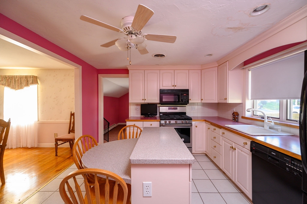 61 Grove Street Braintree, MA 02184 - Photo 7 of 29 a kitchen with stainless steel appliances granite countertop a sink a stove top oven a dining table and chairs with wooden floor