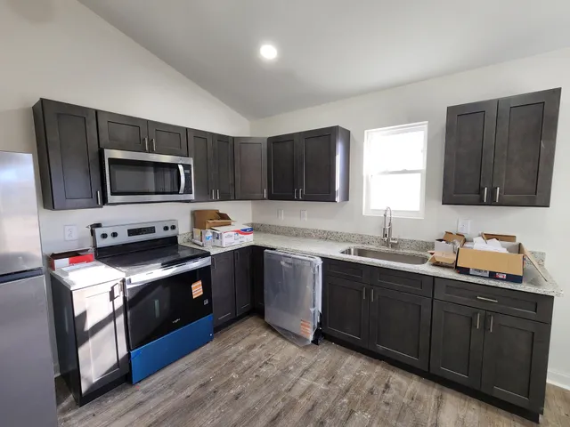 a kitchen with stainless steel appliances granite countertop a stove top oven a sink dishwasher and a microwave oven with wooden cabinets