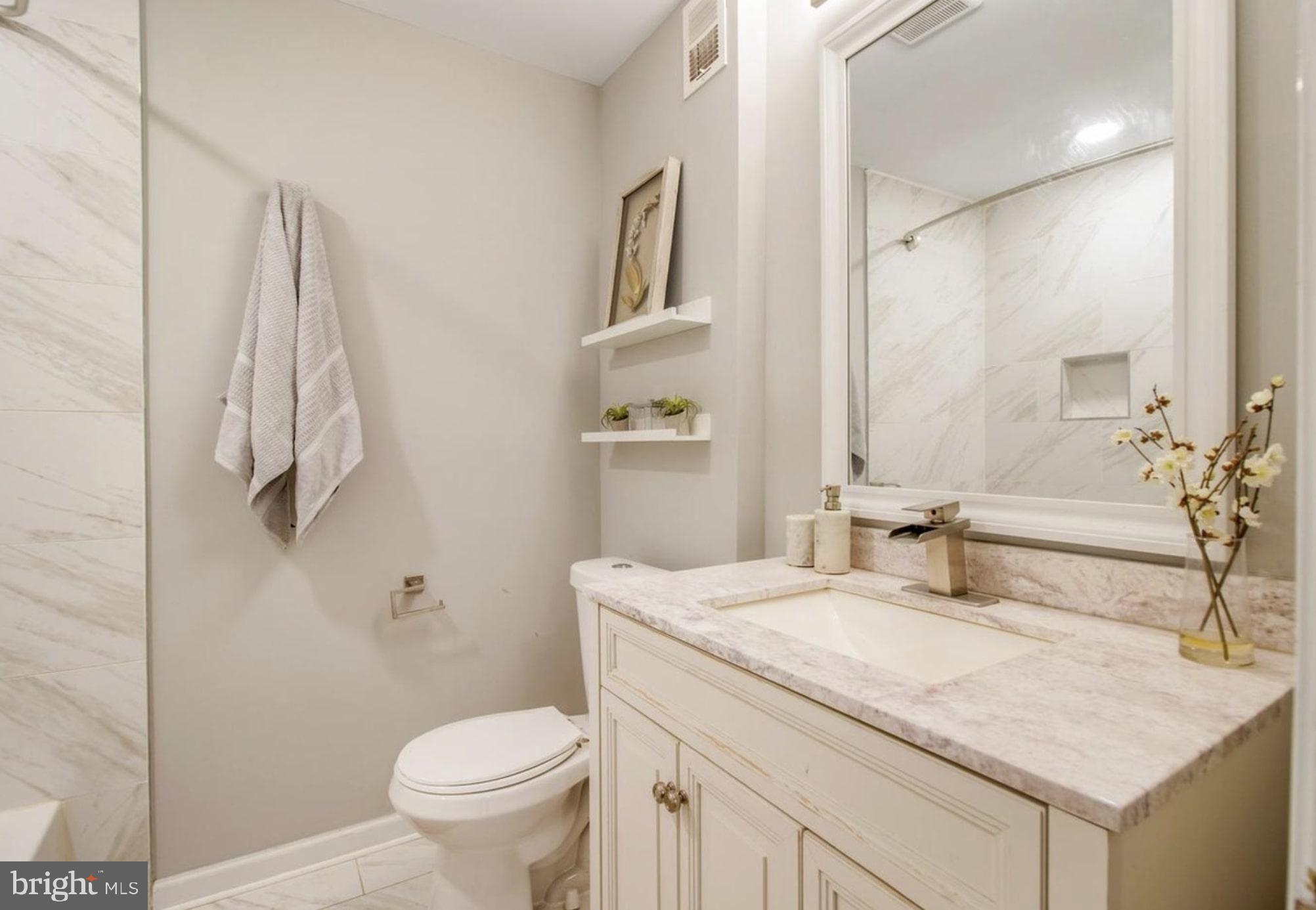 1149 Summit Street Northeast, Unit 2 Washington, DC 20002 - Photo 12 of 14 a bathroom with a granite countertop sink a toilet and a mirror