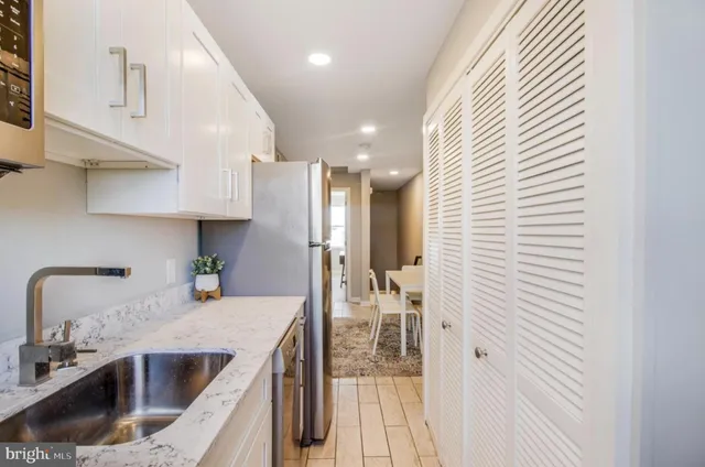 a kitchen with stainless steel appliances granite countertop a sink refrigerator and cabinets