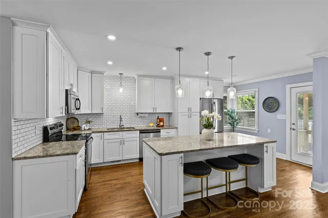 a kitchen with granite countertop kitchen island sink stove and white cabinets