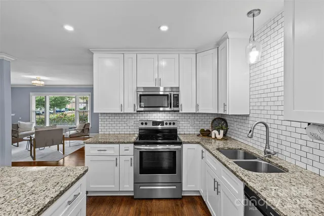 a kitchen with granite countertop a sink stainless steel appliances and cabinets